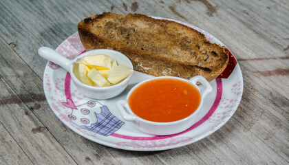piece of bread with butter and jam handmade and on a wooden table