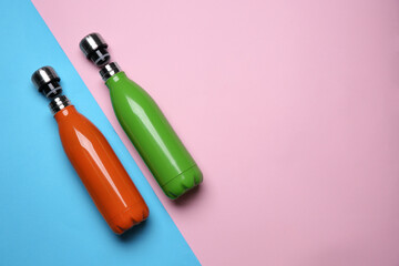 Modern thermo bottles on color background, flat lay. Space for text