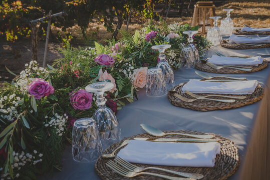 party table in the middle of a vineyard with golden cutlery