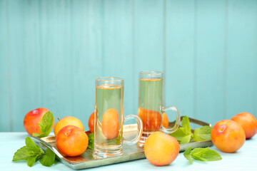 Delicious plum liquor, ripe fruits and mint on table against light blue background, space for text. Homemade strong alcoholic beverage