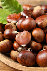 Fresh sweet edible chestnuts in wooden bowl, closeup