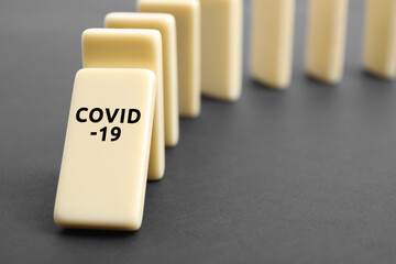 Domino tiles on grey table, closeup. Spreading of coronavirus concept