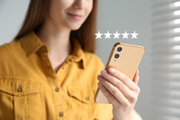 Woman leaving review online via smartphone indoors, closeup. Five stars over gadget - obrazy, fototapety, plakaty