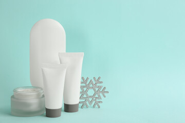 Beautiful composition with cosmetic products on cyan background, space for text. Winter care