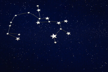 Obraz na płótnie Canvas Zodiac sign Sagittarius on dark sky close up. The applique is made of silver star confetti and grainy blue cardboard. Horoscope Concept. Selective focus.