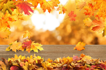 Naklejka na ściany i meble Wooden surface with beautiful autumn leaves on blurred background