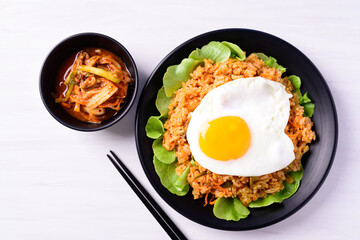 Korean food,  Kimchi fried rice with fried egg on top and fresh kimchi cabbage on white background