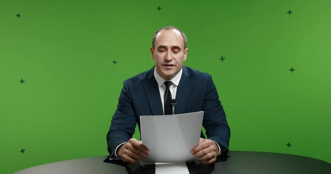 Male television anchor frustrated with script, standing up and walking away. News reporter angry with gutter press and fake news, shot on green chroma key background 4k footage