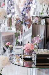 Mirrored boxes and transparent glass vases with pink hydrangea flowers on the table. Wedding decor with mirrors and glass elements in the interior.