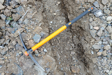pickaxe hoe lying on the ground. hand-held percussion tool designed for working on stone, stony ground, very dense ground