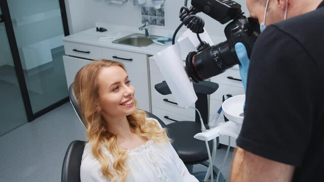 Beautiful woman patient posing for photograph in dental office. Male orthodontist taking picture of female teeth for preventive examination. Treatment. Dentistry. Close-up.