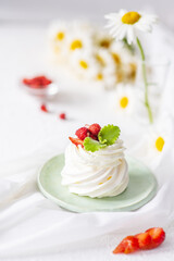 Meringue and whipped cream cake decorated with strawberries and mint on the table
