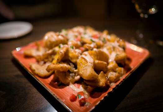 This Closeup Image Shows A Hot Plate Of Delicious Irish Potato Nachos At Restaurant Table.