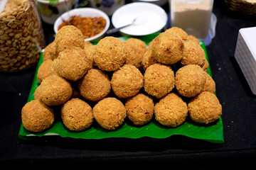 Lines of spicy brown rice and sour pork balls on banana leaf