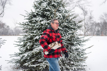 Fototapeta premium Man carrying firewood in winter snow