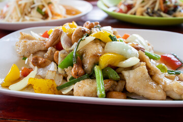 Thai food, chicken cashew nut in front, in the back two different papaya salads