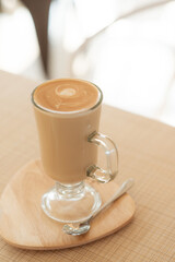 a cup of latte on wood plate.
