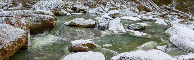 Naklejka na ściany i meble Panorama of a mountain river with stones covered with snow