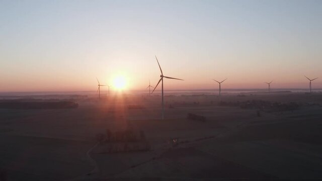 Sun just after sunrise behind wind turbine farm.