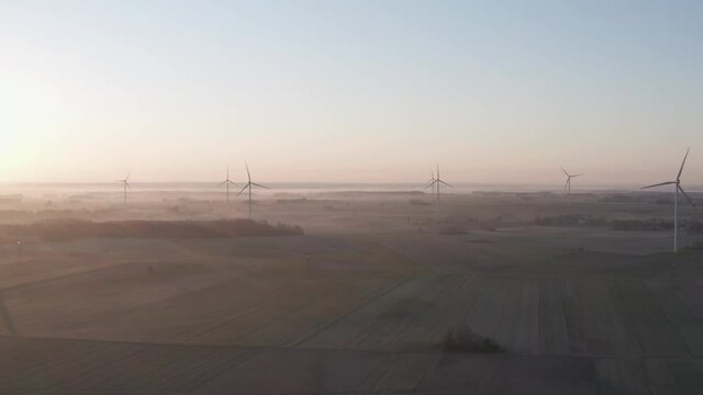 foggy sunrise over wind farm in mazowia, Poland. Drone footage.