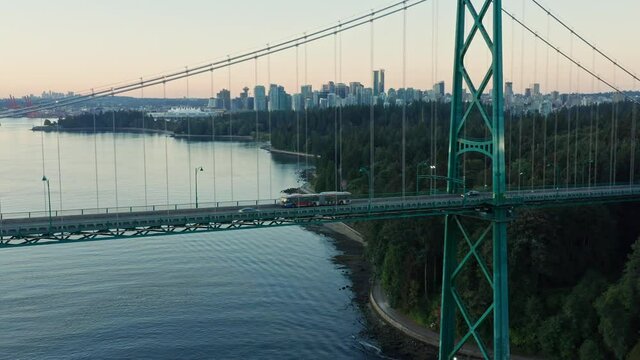 Stunning drone aerial flying upwards showing Lions Gate Bridge and Vancouver  cityscape during sunset - Canda