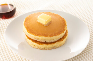 積み重ねたホットケーキにメープルシロップをかけて食べる
