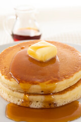 積み重ねたホットケーキにメープルシロップをかけて食べる