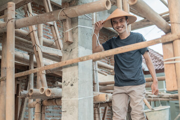 construction workers smile at the camera as they stand between the bamboo and poles in the unfinished house