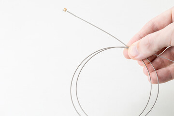 person holding new music string for electric guitar over white background. replacing string on a...