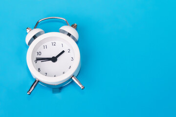alarm clock on blue background, copy space