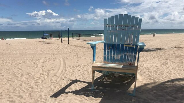 Fort Lauderdale Beach Sidewalk at Midday in a summer season with a tourist big chair for pictures, o back a few people enjoying the weekend during the Corona Virus Pandemic illness breakdown.