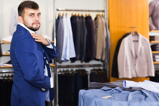 Adult male customer choosing jacket in men clothes shop