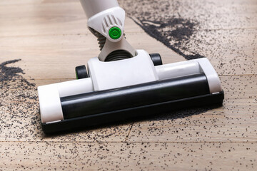 A man uses a bagless vertical cordless vacuum cleaner to clean floor.