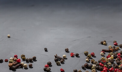 Pepper mix and cloves. Black, red and white peppercorns isolated on black stone background. Close-up, copy space