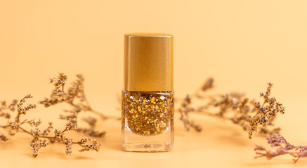 Nail polish of beautiful gold colors on orange background.