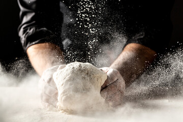Photo of flour and men hands with flour splash. Cooking bread. Kneading the Dough. Isolated on dark background. Empty space for text