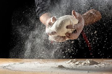 Hands of baker kneading dough isolated on black background. prepares ecologically natural pastries