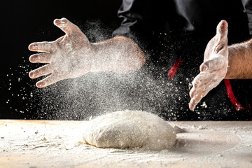 White flour flying into air as pastry chef in white suit slams ball dough on white powder covered table. concept of nature, Italy, food, diet and bio.