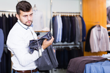 Adult guy choise new pair of pants in fashion department