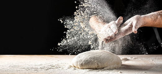 Photo of flour and men hands with flour splash. Cooking bread. Kneading the Dough. Isolated on dark...
