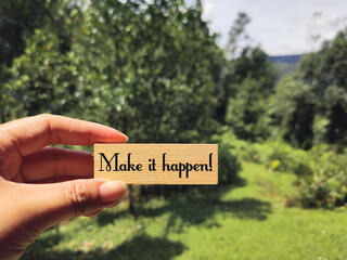 Inspirational and motivational quote - Make it happen written on wooden block background. Stock photo.