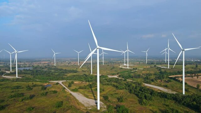 Many wind turbines for generating electricity on the grasslands with mountains and sky as a background in Thailand.