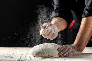 Photo of flour and men hands with flour splash, ball dough on white powder covered table. concept...