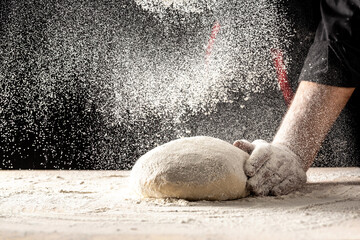 Photo of flour and men hands with flour splash, ball dough on white powder covered table. concept of nature, Italy, food, diet and bio
