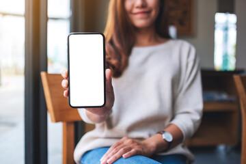 Mockup image of a beautiful asian woman holding and showing a mobile phone with blank white screen