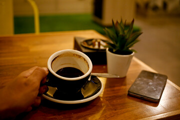 hand holding empty cup of coffee on a table