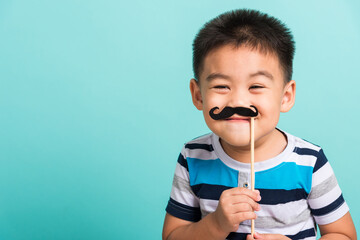 Funny happy hipster kid holding black mustache props for the photo booth close face, studio shot...