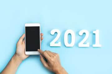 Hand holding empty screen smart phone on color background with 2021 new year concept and copy space