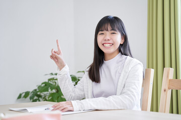 リビングで笑顔で指差しをする日本人女子中学生