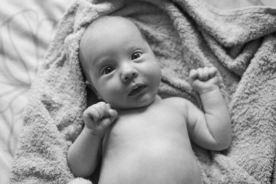 A black and white photo of a naked baby in a towel
